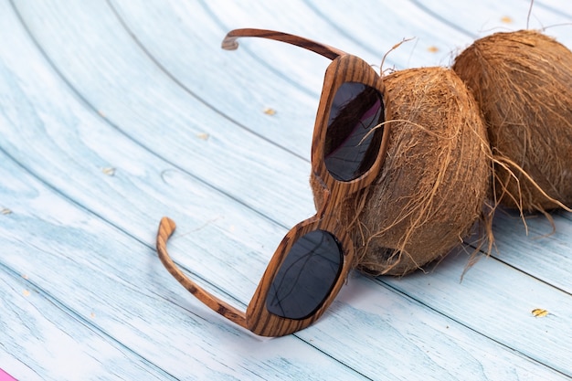 Noix de coco entières et verres en bois sur un fond en bois bleu