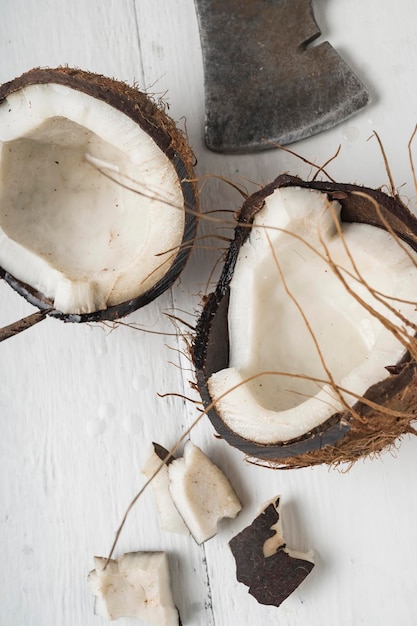 Une noix de coco est coupée en deux sur une table en bois clair Vue de dessus