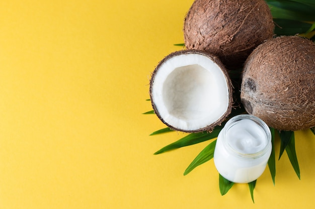 Noix de coco avec des feuilles vertes sur fond jaune.