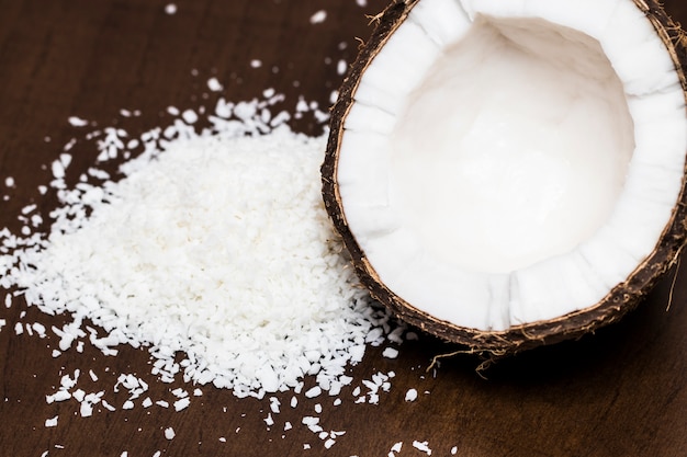 Noix de coco avec des flocons de noix de coco isolés sur le fond en bois