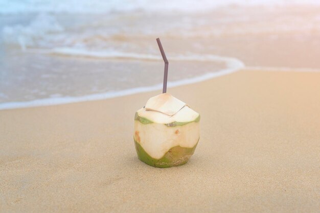 Noix de coco fraîche avec paille sur le concept de voyage et de vacances à la plage