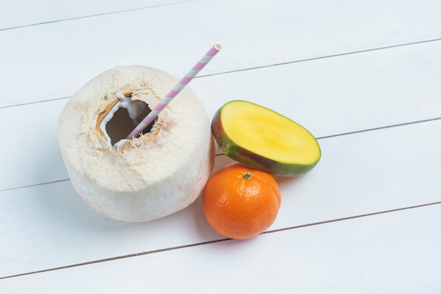 Noix de coco fraîche avec paille, moitié de mangue et mandarine