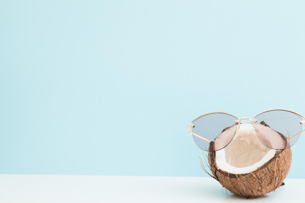 Noix de coco fraîche portant des lunettes de soleil sur fond de couleur Bonjour l'été