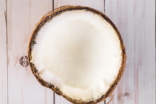 Noix de coco fraîchement ouverte sur fond de bois.