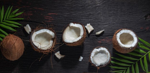 Noix de coco hachée sur un fond en bois, vue de dessus. Le lait de coco et les flocons de noix de coco sont des aliments tropicaux