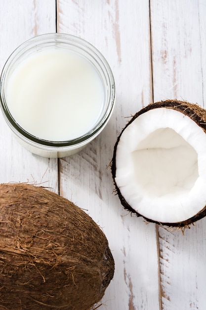 Noix de coco et lait de coco sur la vue de dessus de table en bois blanc