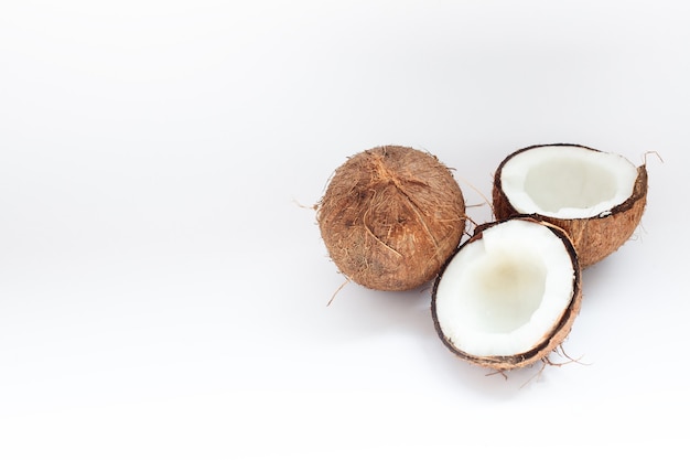 Noix de coco mûres et moitié de noix de coco sur mur blanc