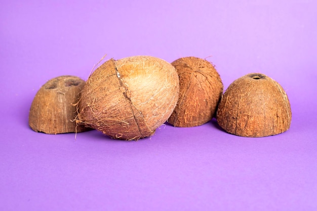 Noix de coco pelée avec des moitiés. Noix de coco cassée sur un fond coloré