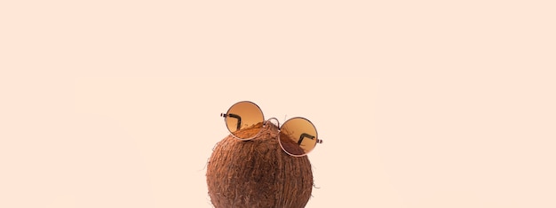 Les noix de coco portent des lunettes de soleil sur fond rose. Concept de vacances sous les tropiques ensoleillés