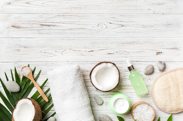 Noix de coco avec pots d'huile de noix de coco et crème cosmétique sur fond coloré Vue de dessus Espace libre pour votre texte Cosmétiques naturels à la noix de coco et concept de traitement biologique Composition du spa à la noix de coco