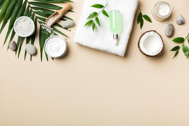 Noix de coco avec pots d'huile de noix de coco et crème cosmétique sur fond coloré Vue de dessus Espace libre pour votre texte Cosmétiques naturels à la noix de coco et concept de traitement biologique Composition du spa à la noix de coco