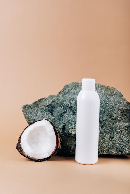 Noix de coco et un tube de cosmétiques sur fond de pierre