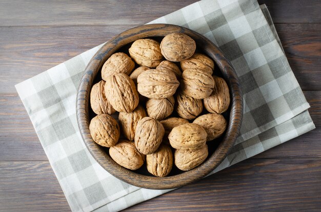 Noix dans une assiette sur un fond en bois marron. Les noix sont une source de protéines végétales