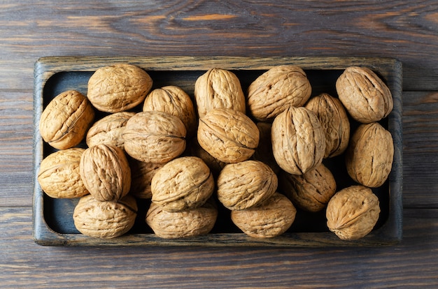 Noix dans une assiette sur un fond en bois marron. Les noix sont une source de protéines végétales