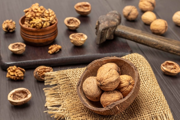 Noix entières dans des coquilles de noix de coco sur toile de jute Cerneaux de noix dans un bol en bois