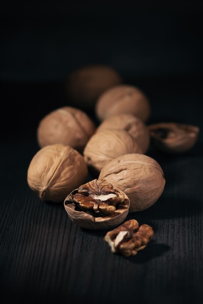 Photo les noix entières et ouvertes se bouchent sur un fond en bois foncé. fond de nourriture avec des noix dans un style rustique, copiez l'espace. concept d'alimentation saine