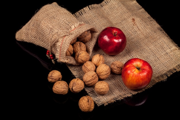 Noix entières et pommes sur une table sur un fond noir