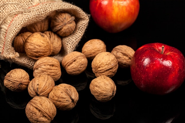 Noix entières et les pommes sur une table sur un fond noir