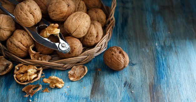 Noix fraîches avec un casse-noix sur une table en bois bleue