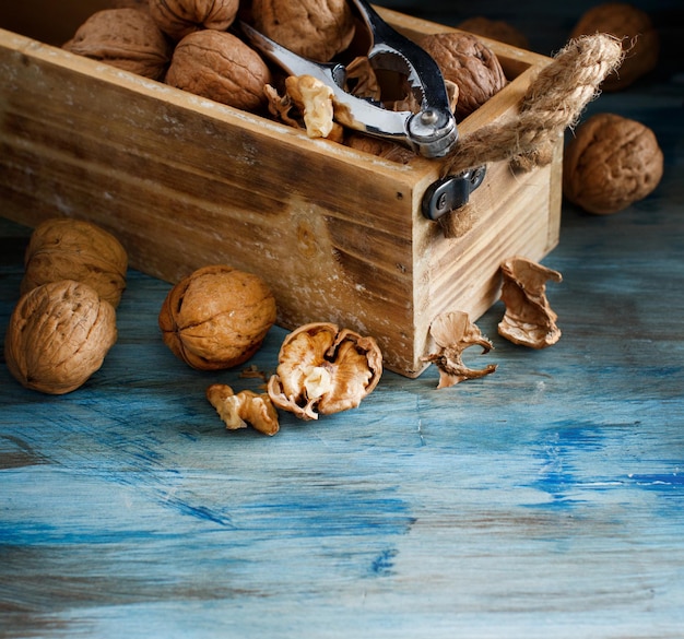 Noix fraîches avec un casse-noix sur une table en bois bleue