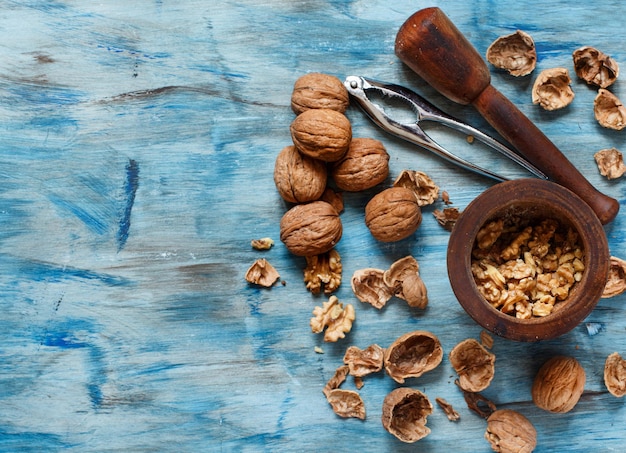 Noix fraîches avec mortier et pilon sur une table en bois bleue se bouchent