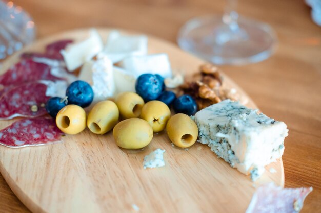 Noix de fromage olives sur un plateau en bois sur la table des collations pour le vin