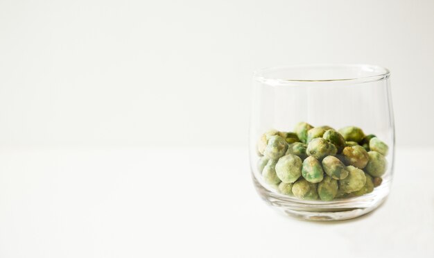 noix de haricot rôtie au wasabi vert snack dessert dans un verre sur fond blanc.