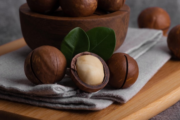 Noix de macadamia bio dans un bol et une cuillère en bois. Superfood et concept d'aliments sains.