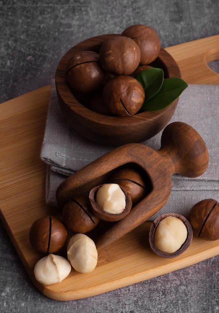 Noix de macadamia bio dans un bol et une cuillère en bois. Superfood et concept d'aliments sains.