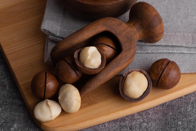 Noix de macadamia bio dans un bol et une cuillère en bois. Superfood et concept d'aliments sains.