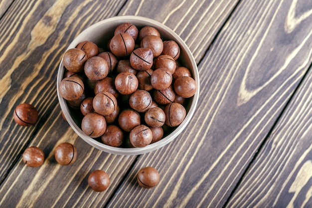 Noix de macadamia dans un bol sur une table en bois avec espace de copie. Top wiew.