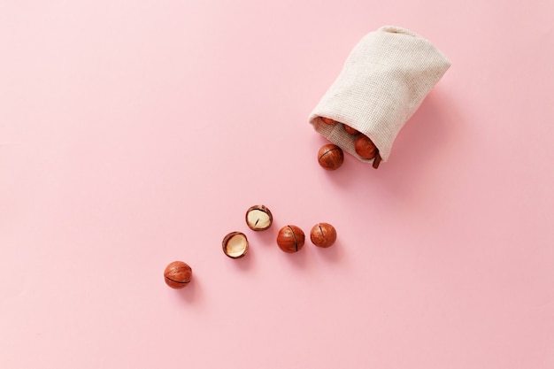 Noix de macadamia dans un sac sur fond rose