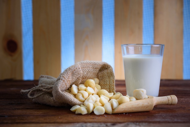 Noix de macadamia fraîche avec un verre de lait sur le fond en bois.