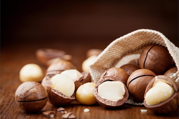 Photo noix de macadamia naturelles dans un sac en toile sur une table en bois