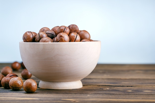 Noix de macadamia. Sur une table en bois sur fond gris avec espace de copie