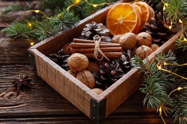 Noix, noisettes, cônes, oranges dans une boîte en bois