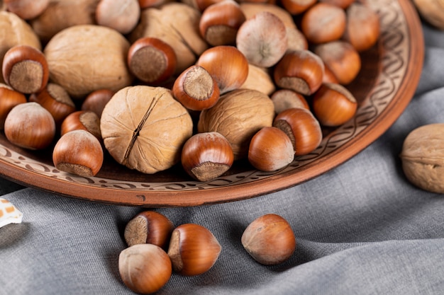 Noix et noix dans un bol en poterie sur une nappe bleue