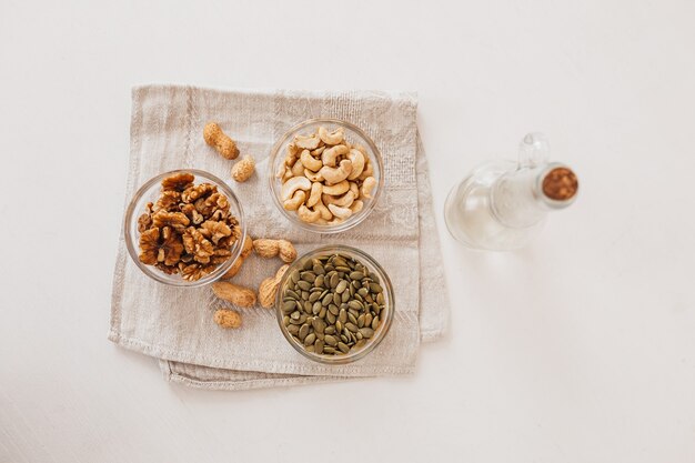 Noix et vinaigre sur un torchon en lin sur un tableau blanc. Noix, noix de cajou et graines de citrouille pour une bonne nutrition. aliments sains et nutriments pour le cerveau et le corps