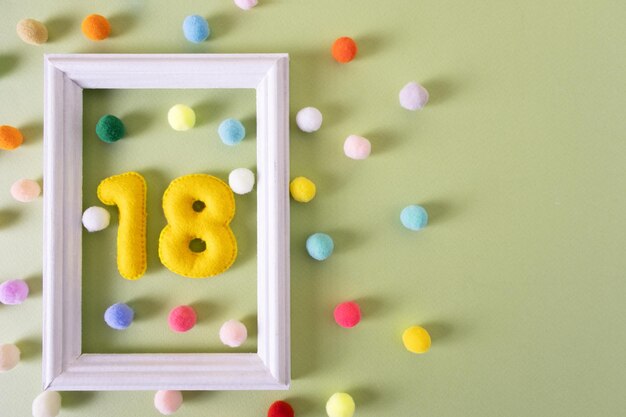 Photo le nombre dix-huit pour un anniversaire dans un cadre blanc avec des boules colorées anniversaire de fête de concert festif