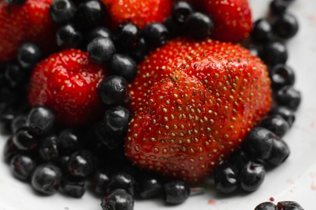 De nombreuses baies de fraises rouges mûres fraîches juteuses avec des mûres isolées sur fond blanc