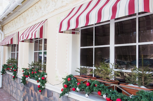 Photo de nombreuses boules de sapin de noël brillantes et scintillantes sur les fenêtres d'un café-restaurant