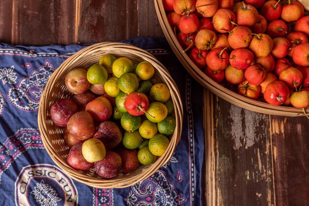 De nombreuses couleurs et variétés de fruits sont soit sur l'assiette, soit éparpillées sur la table en bois.