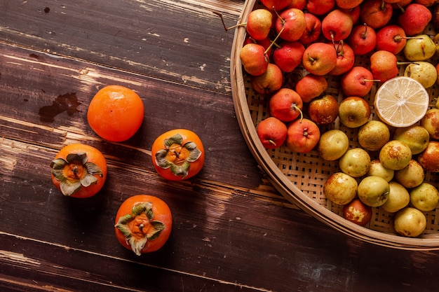 De nombreuses couleurs et variétés de fruits sont soit dans l'assiette, soit dispersées sur la table en bois