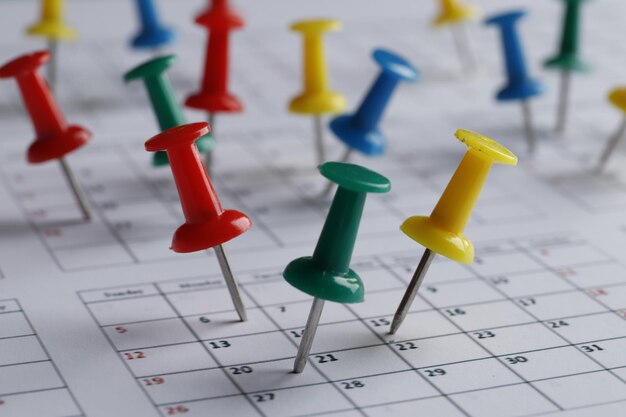 De nombreuses épingles multicolores de différentes dates sur un gros plan de calendrier. Date importante. Place pour le texte. Notion de planification.