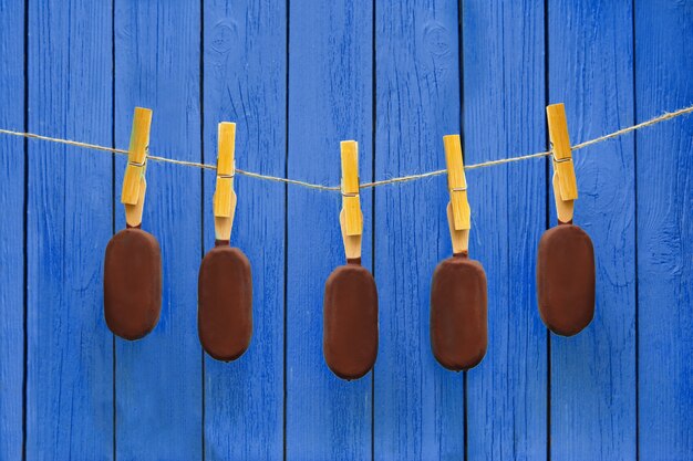 De nombreuses glaces au chocolat suspendues à une corde près d'un fond bleu. été chaud. concept de nourriture délicieuse