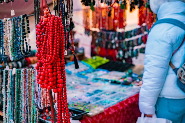 De nombreuses perles colorées de différentes couleurs se vendent à l'extérieur. Bijoux traditionnels faits à la main. Rouge. Ville. Marché. Échanger. Commerce. Colliers. rue