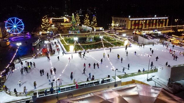De nombreuses personnes patinent sur une belle patinoire en plein air décorée de l'illuminat de noël du nouvel an