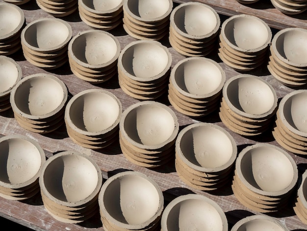 De nombreuses petites assiettes de forme ronde en terre céramique et séchées au soleil. Procédé de fabrication de la faïence.