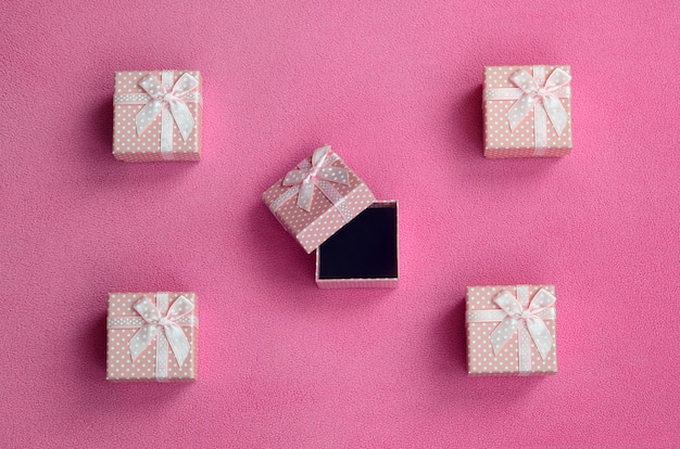 De nombreuses petites boîtes-cadeaux de couleur rose avec un petit noeud reposent sur une couverture