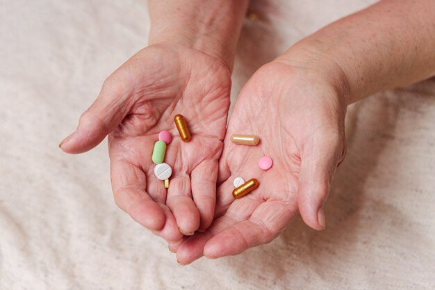 De nombreuses pilules différentes dans les mains d'une personne âgée.